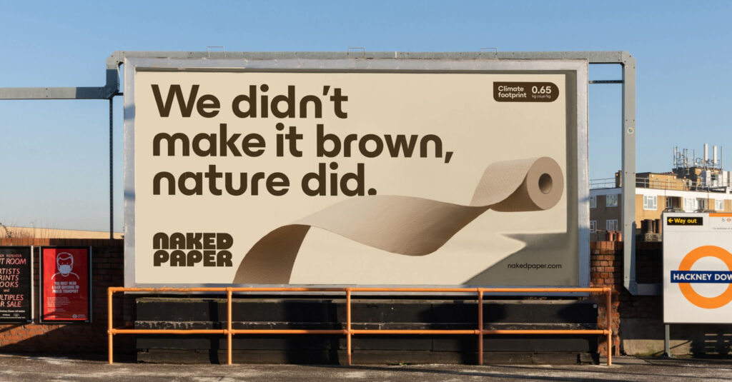A billboard with a brown-toned advert for Naked Paper featuring an illustration of an unraveling toilet roll