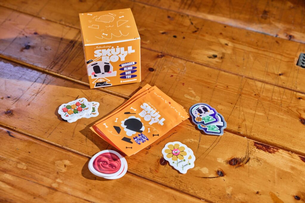 Mix of die-cut character stickers and simpler shaped stickers alongside Skully packaging, illustrating how expressive designs use custom cuts while informational elements use cleaner shapes