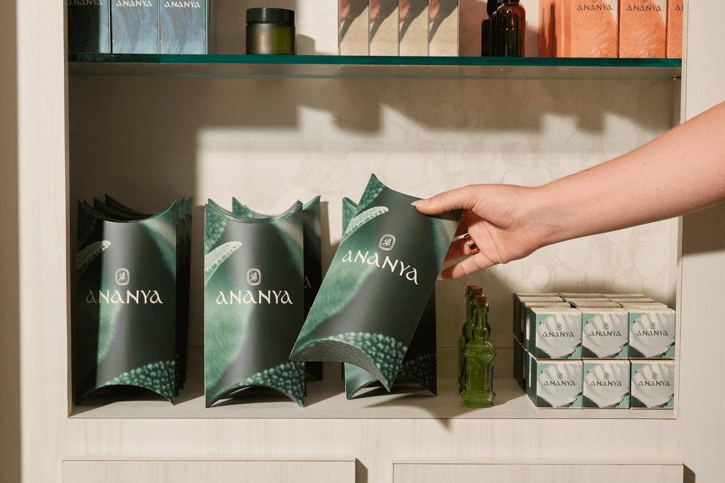 A hand reaching out to a row of stacked branded packages standing along with smaller branded boxes and bottles