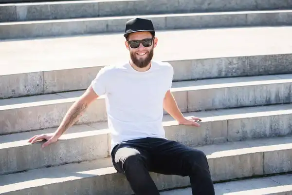 Person wearing a plain white T-shirt and black trousers while sitting on outdoor steps.