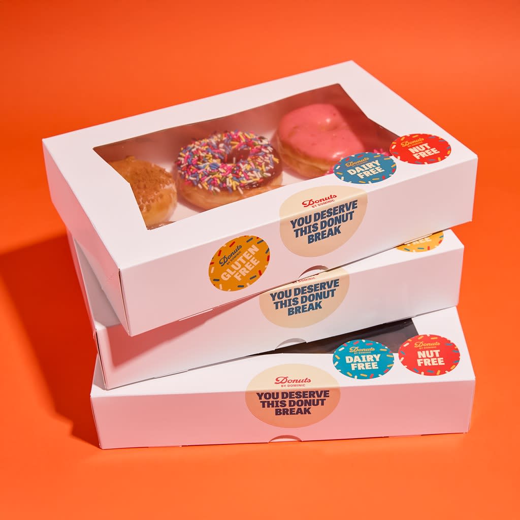A stack of donut boxes with the sticker reciting the slogan “You deserve this donut break”.