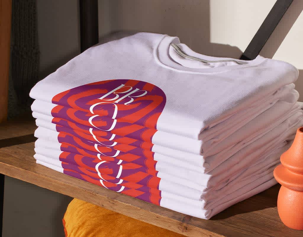 A stack of folded white T-shirts with a red and purple circular design.