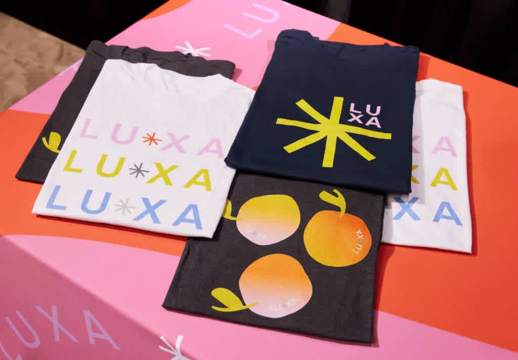 A table with a display of black and white T-shirts with colorful branding.