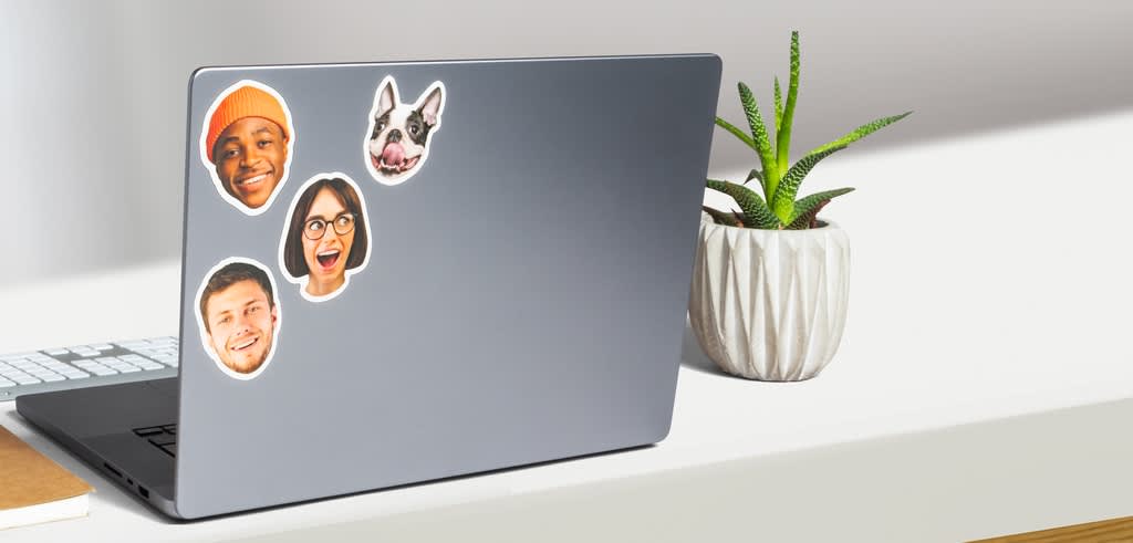 Die-cut face sticker singles stuck on an office work laptop.