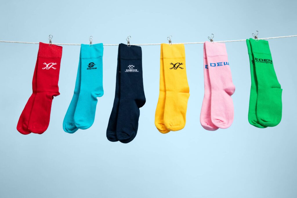 Six pairs of multi-colored branded socks with brand logos.