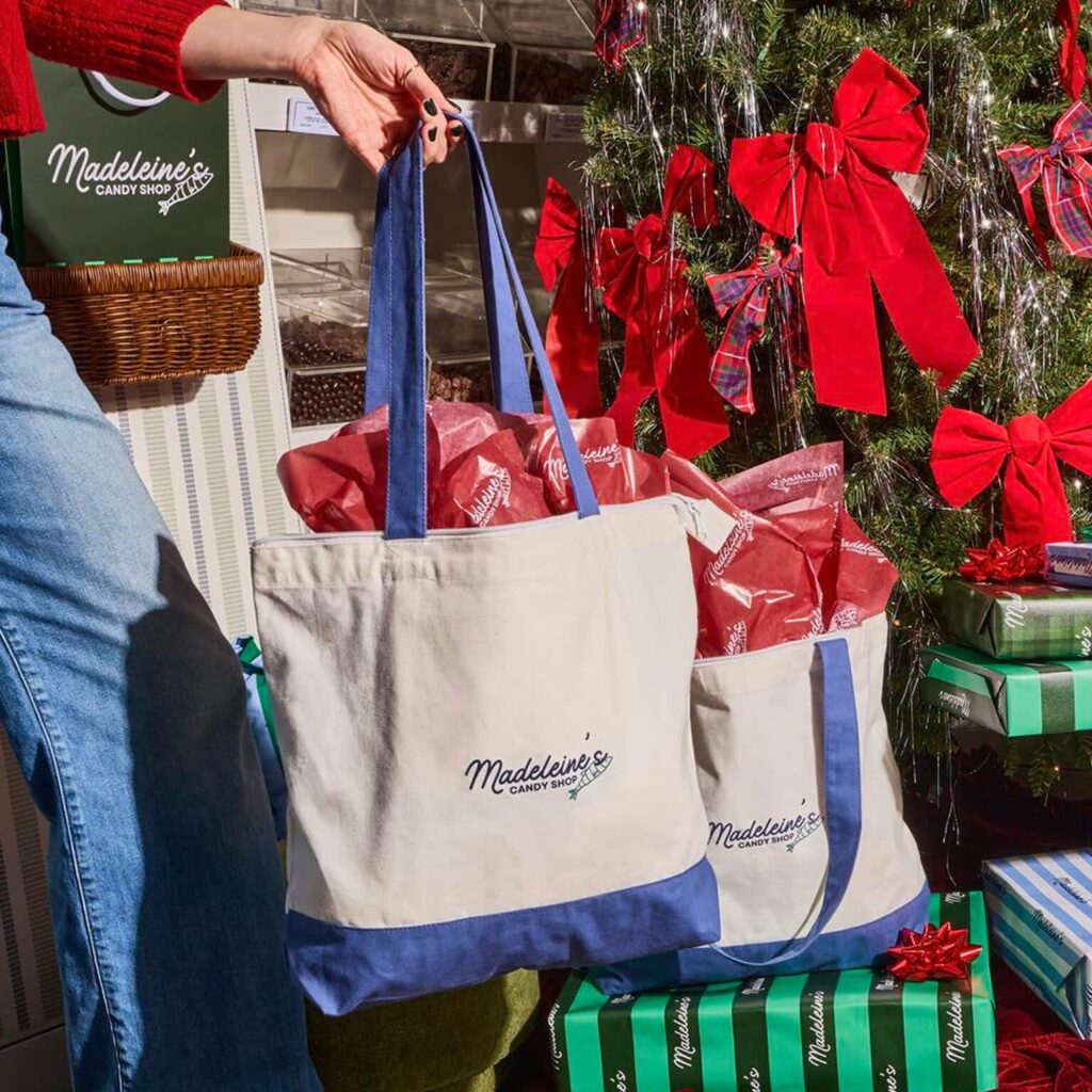 A person holding a personalized tote bag with company branding.