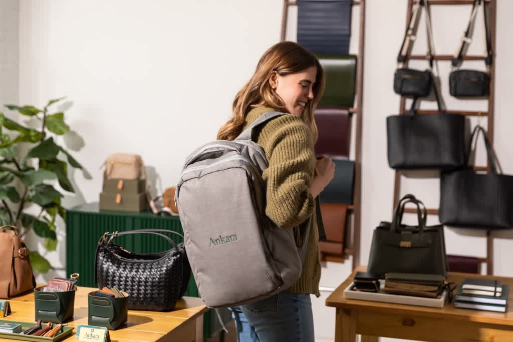 Woman with a gray tech backpack with a dark green logo, client gifts.