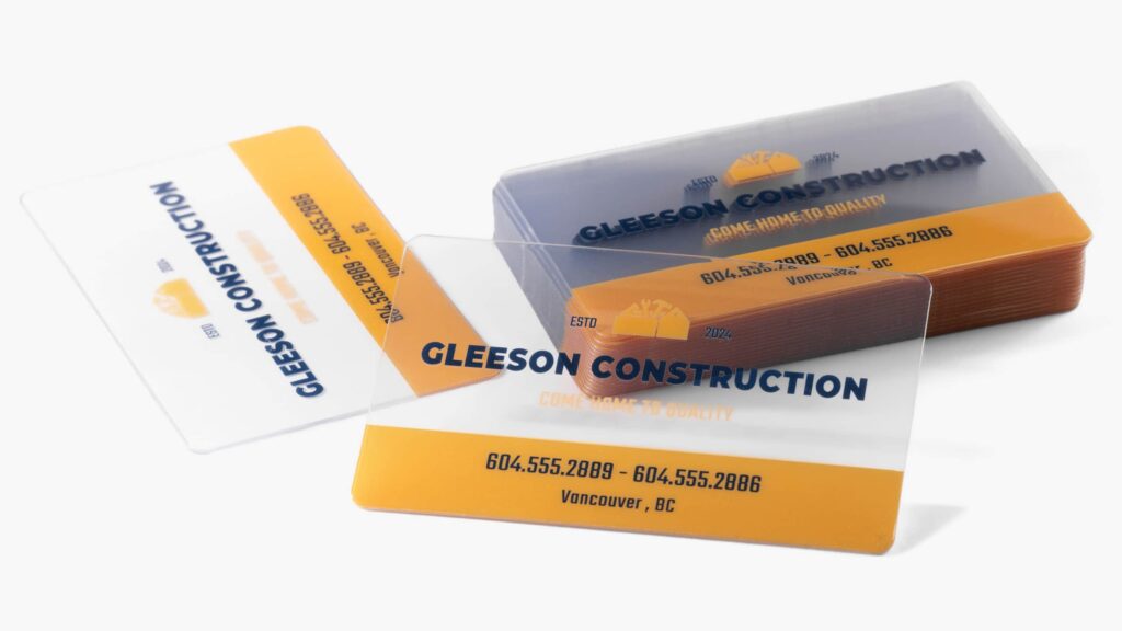 Clear plastic business cards with orange accents and construction company branding.