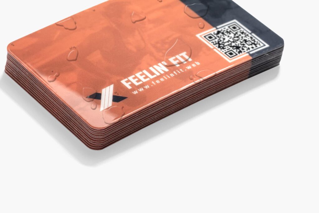 Waterproof orange business cards with water droplets, fitness branding and a QR code.