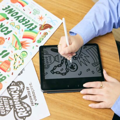 Person sketching on a graphic tablet at a wooden desk, illustrating the elements of design in action.