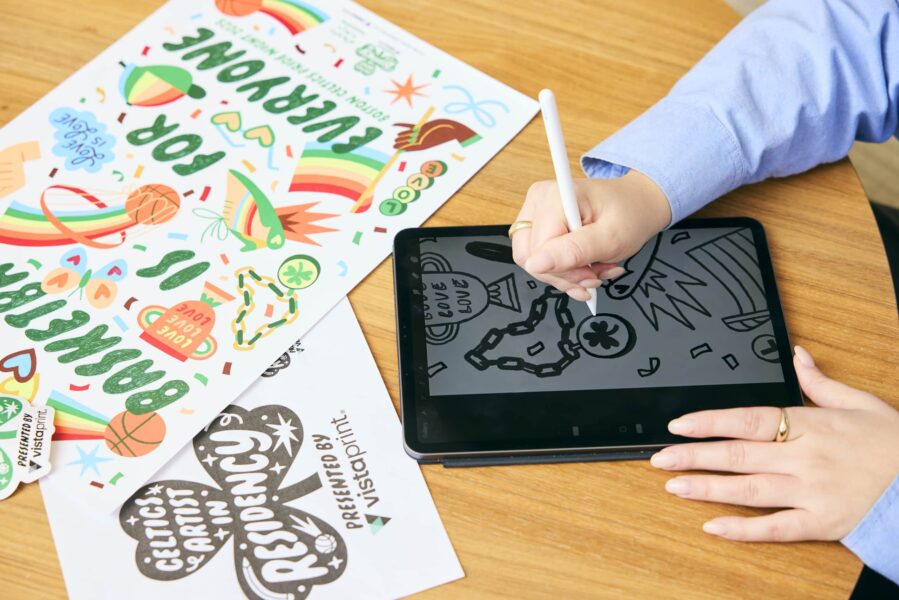 Person sketching on a graphic tablet at a wooden desk, illustrating the elements of design in action.
