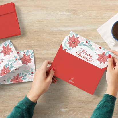 top view of signing and sealing Christmas cards at a desk with a coffee