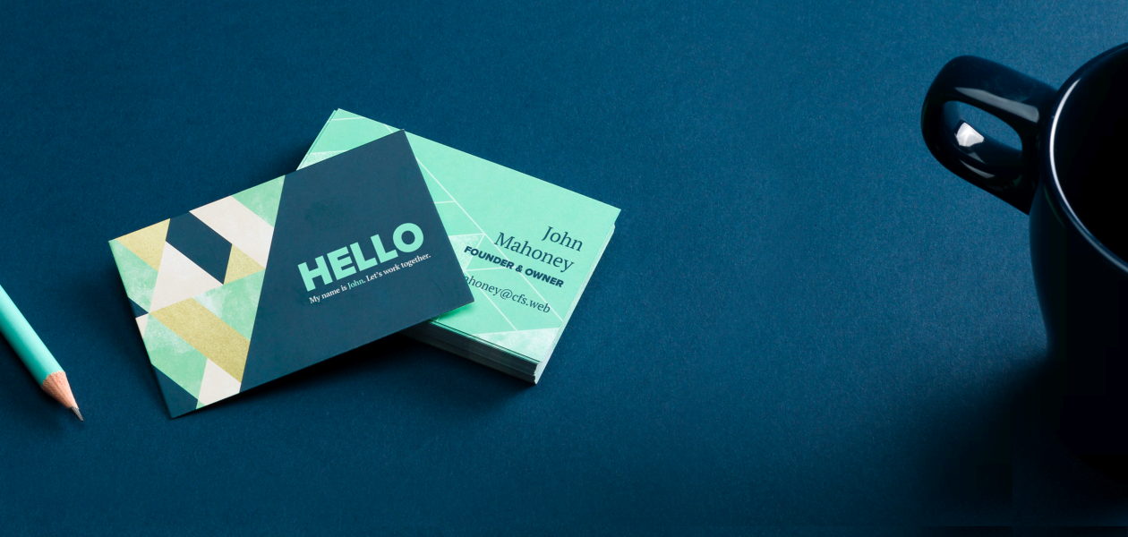 A geometric business card in green and blue tones, alongside a pencil and a cup. A perfect example of PDF template creation.