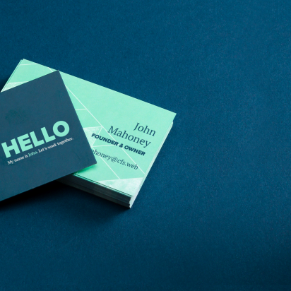 A geometric business card in green and blue tones, alongside a pencil and a cup. A perfect example of PDF template creation.