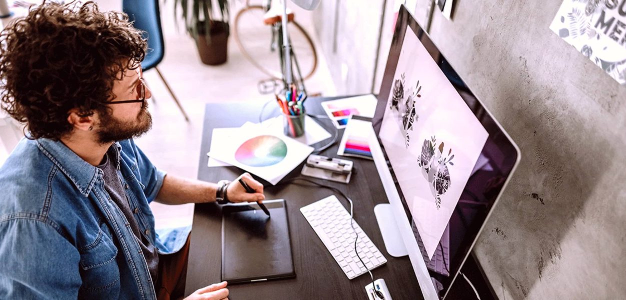 A person sitting at the computer look at their design