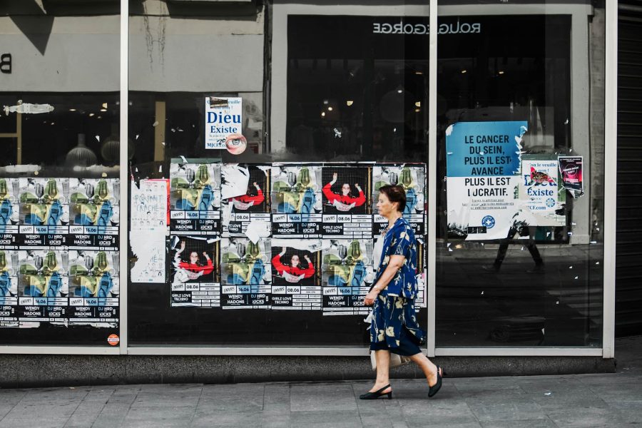 woman walking past window of posters