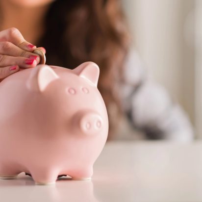 A woman putting a coin into a piggy bank