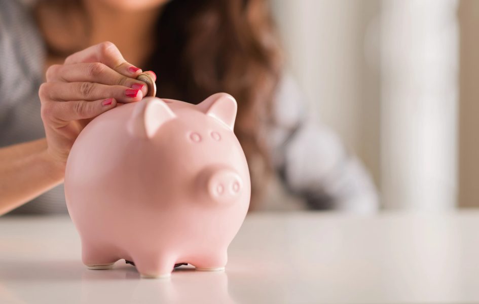A woman putting a coin into a piggy bank