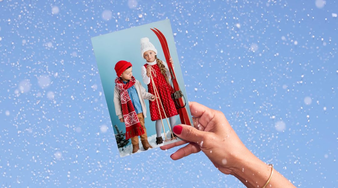 hand holds photo of kids dressed in ski clothes