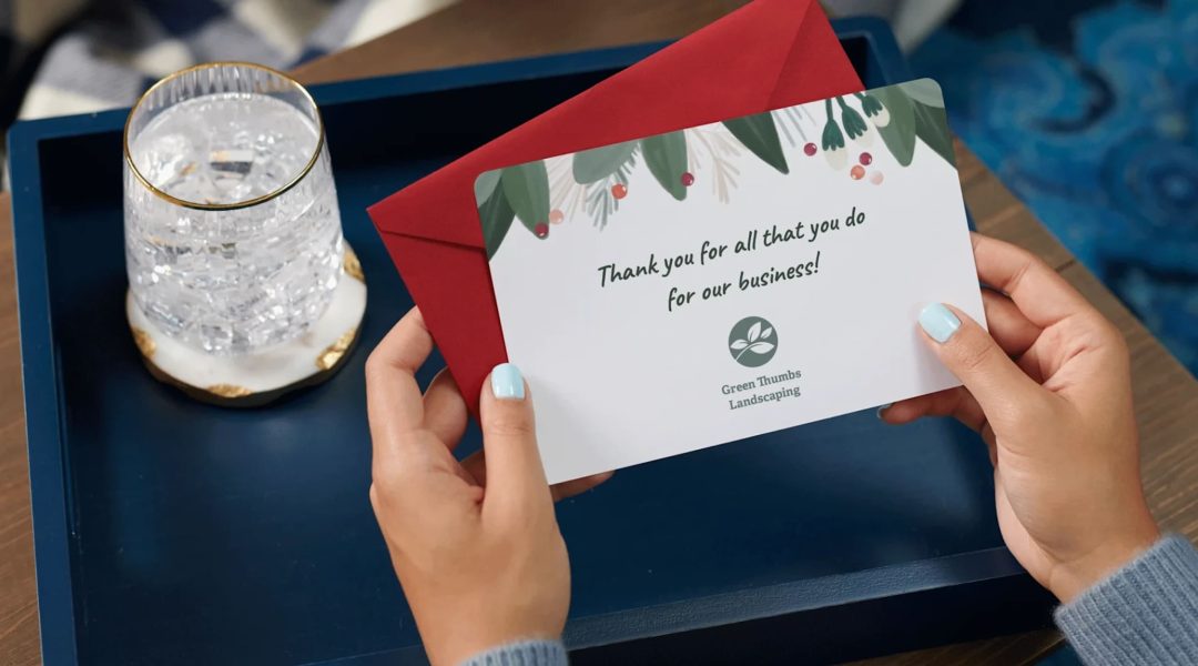 person holds up branded thank you card