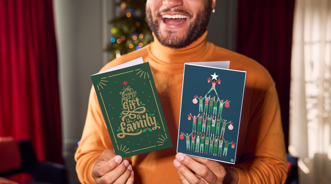 person smiles holding Christmas cards up