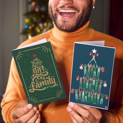 person smiles holding Christmas cards up