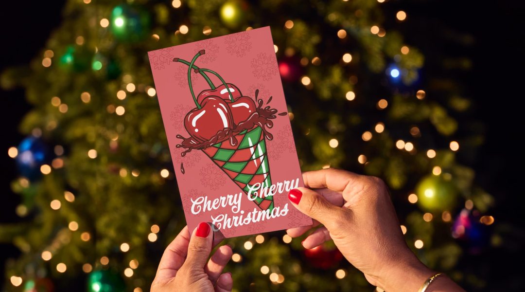 hands hold card in front of Christmas tree