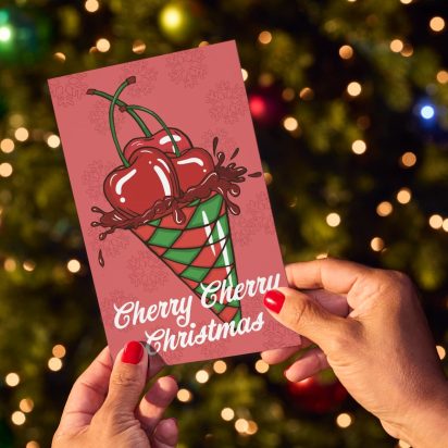 hands hold card in front of Christmas tree