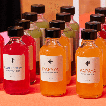 Colorful eco-friendly brand bottles with different superfruit shots labeled papaya, elderberry, and more.