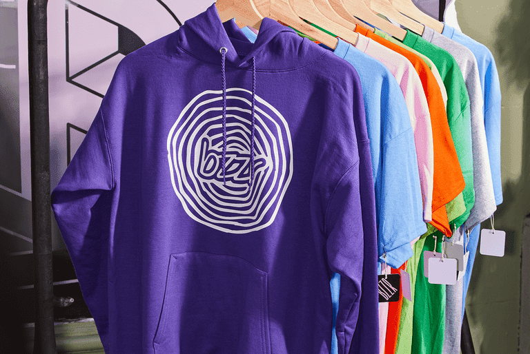 Colorful long-sleeve hoodies with custom logos hanging on a shop rack