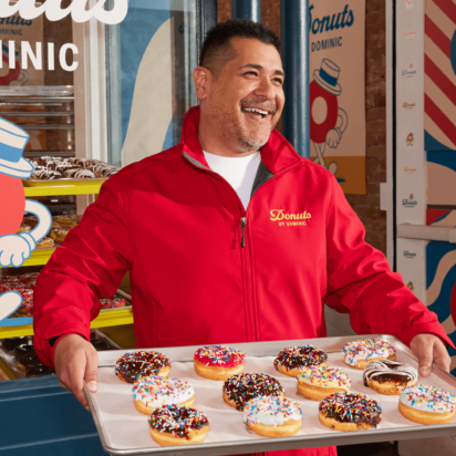 A donut shop employee wearing a branded uniform