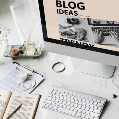 Image of an open desktop and keyboard with paper and pens beside it on the wider deskspace.