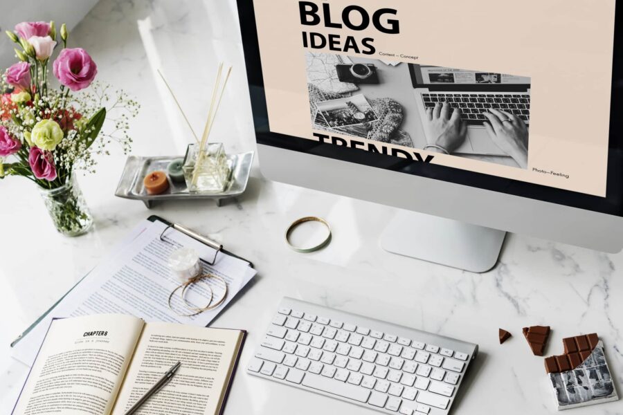 Image of an open desktop and keyboard with paper and pens beside it on the wider deskspace.