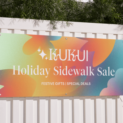 Colorful promotional banner hanging on a white fence, showcasing festive branding and message – example of banner materials in use.