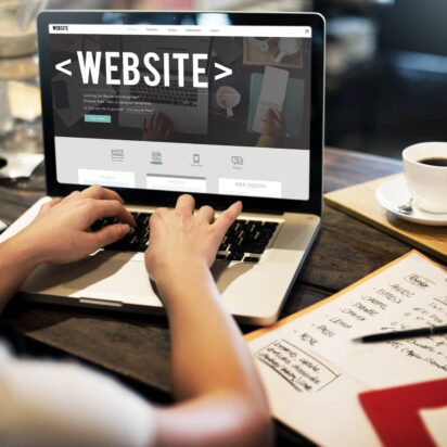 Person typing on a laptop, picture from behind so you see the word "Website" on the screen of the laptop.