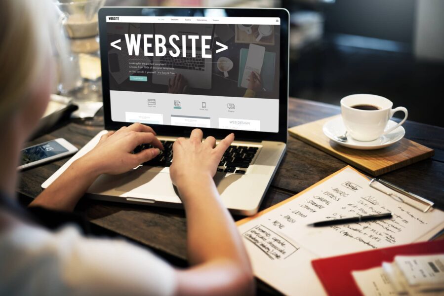 Person typing on a laptop, picture from behind so you see the word "Website" on the screen of the laptop.