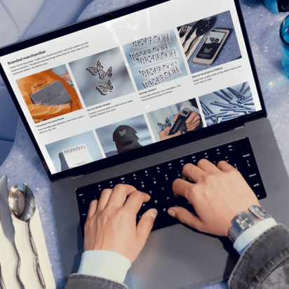 Male hands working on a notebook at a café-style desk, researching the costs of website hosting.