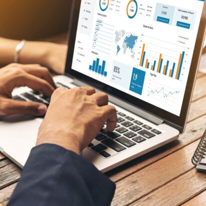 Male and female hands analyzing website traffic data using documents, notebooks, and a laptop — google tag management concept.