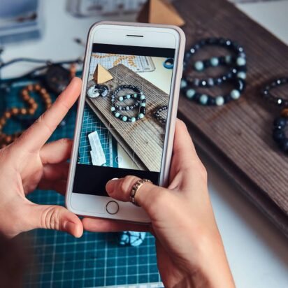 Small business owner photographing handmade bracelets for Instagram marketing.