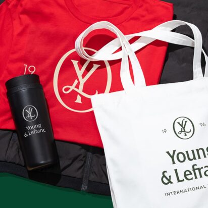 A top down image of a festively colored and branded tshirt, water bottle and tote bag