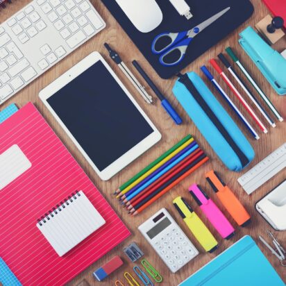 Flat lay of colorful notebooks, pencils, markers, and digital tools on a desk, representing personalized school supplies.