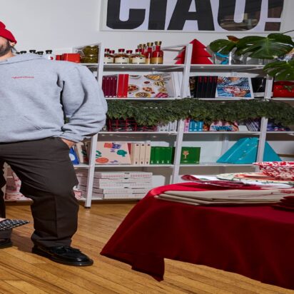 Business holiday prep example: three smiling people wearing branded Aperitivo accessories, t-shirts, and promotional materials in the background.