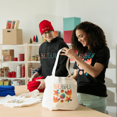 Two people preparing branded tote bags with colorful designs, showcasing creative swag bag ideas for events and businesses.