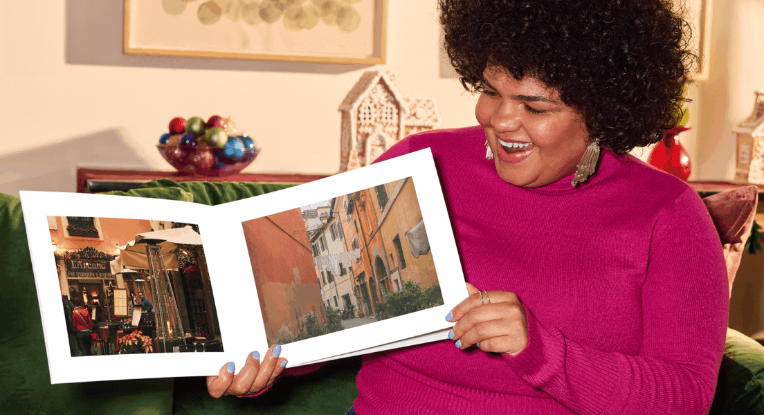 Smiling woman holding her custom photo book, proud of her creation.