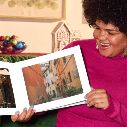 Smiling woman holding her custom photo book, proud of her creation.
