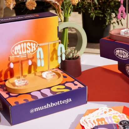 Colorful trade show booth displaying branded jewelry packaging boxes used as both packaging and product displays.