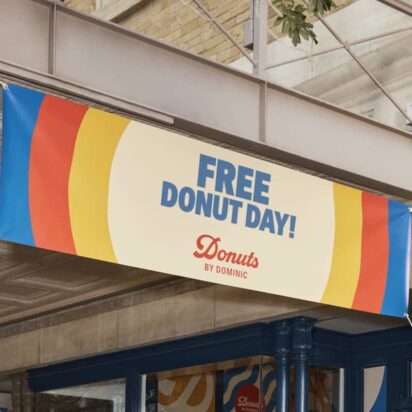 Donut company's overhead outdoor colourful (blue red and yellow borders) sign advertising "Free donut day!".