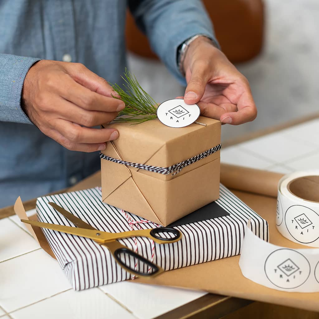 Man finishing customized packaging to ship by adding a branded sticker