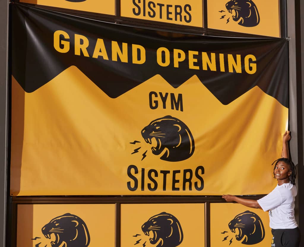 A bold yellow and black logo for a women’s gym hanging banner