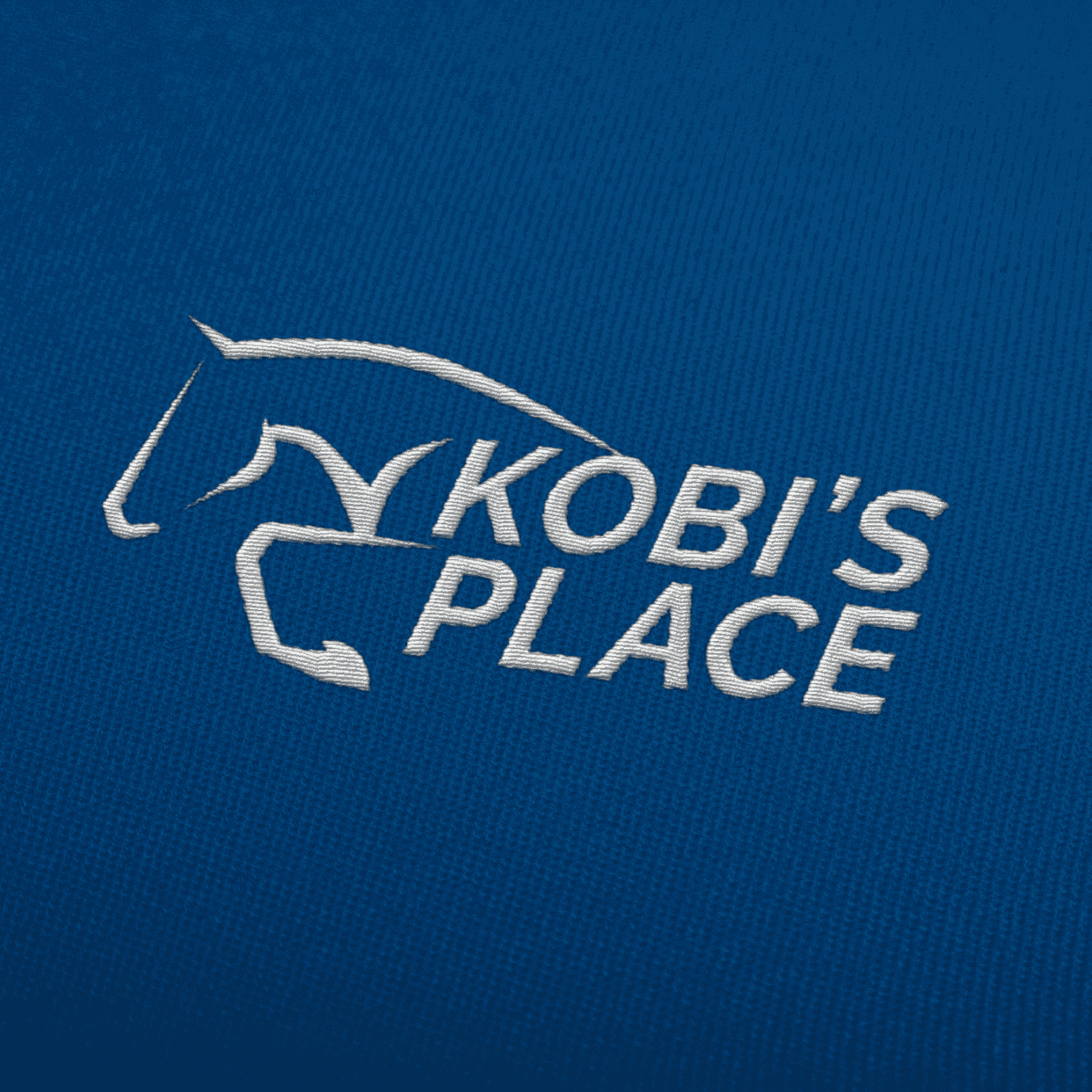 A close-up of a white brand logo printed on navy-blue fabric via embroidery